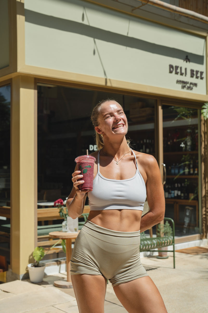 The coach is smiling while holding a cup of juice.